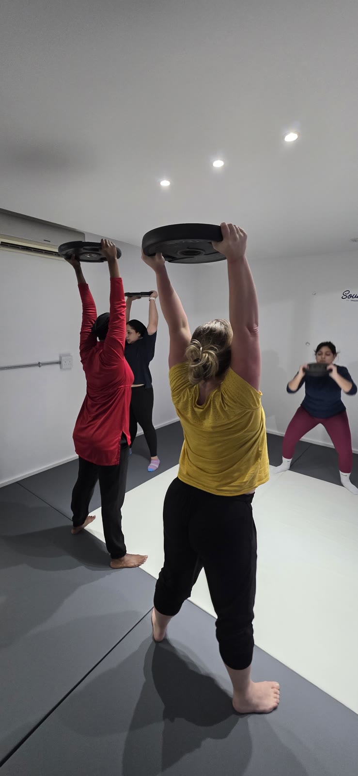 Fit Circle members lifting weight plates together during class