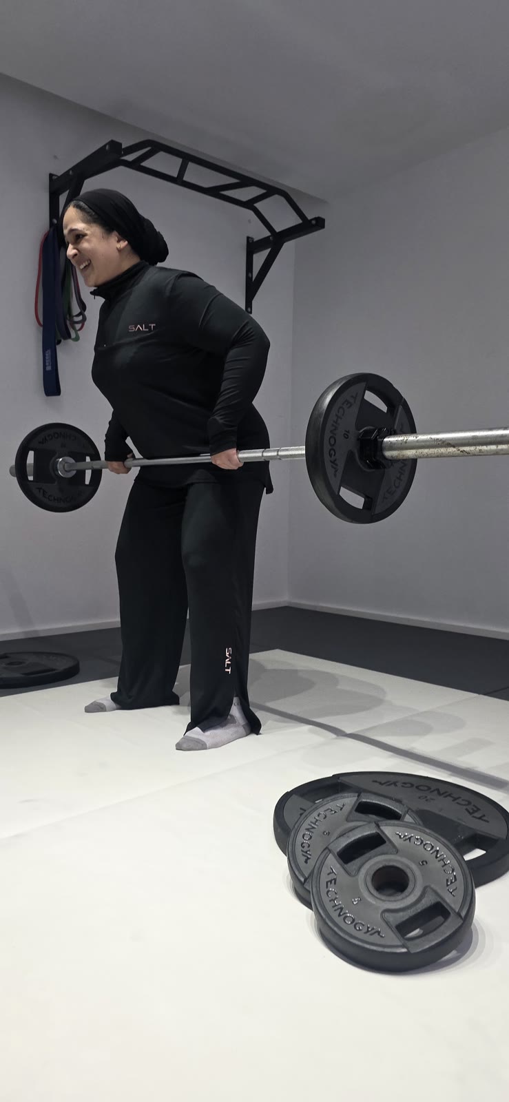 A smiling Fit Circle member lifting a barbell during class
